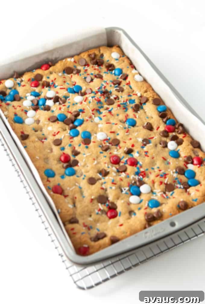freshly baked 9x13 pan of fourth of july monster cookie bars, golden brown and glistening with melted chocolate