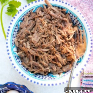 Bowl of incredibly tender Instant Pot shredded beef, perfectly cooked and ready for a variety of Mexican dishes like tacos and burritos.