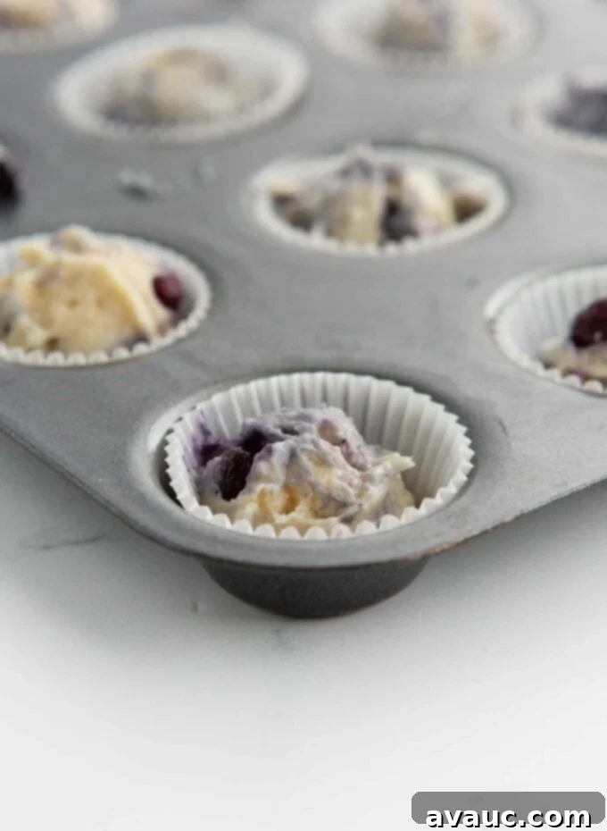 Bite-Sized Blueberry Muffins 7 mini blueberry muffin batter scooped into paper liner in mini muffin pan