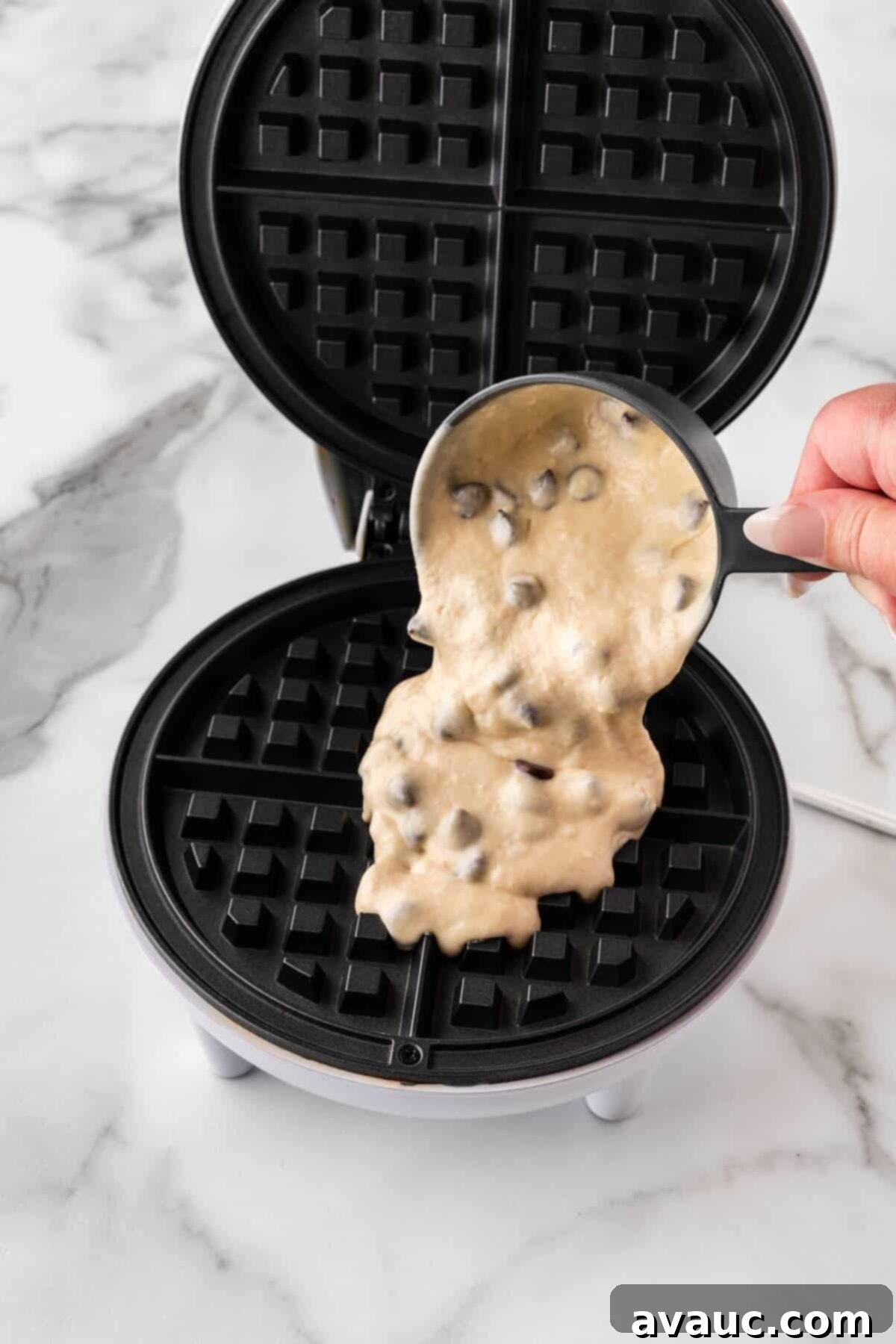 Golden Blueberry Crunch Waffles 13 Pouring blueberry waffle batter into a hot waffle iron.
