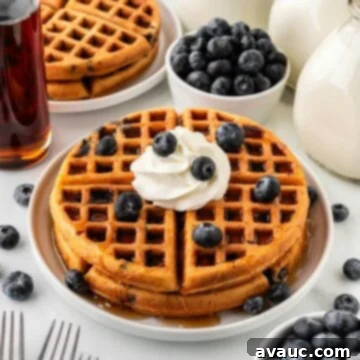 Golden Blueberry Crunch Waffles 18 Stack of blueberry waffles with whipped cream and fresh blueberries on top.