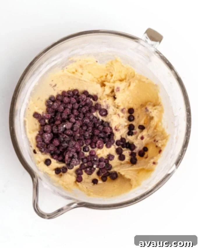 Bowl of wild blueberry muffin batter, showcasing the thick consistency and scattered blueberries.