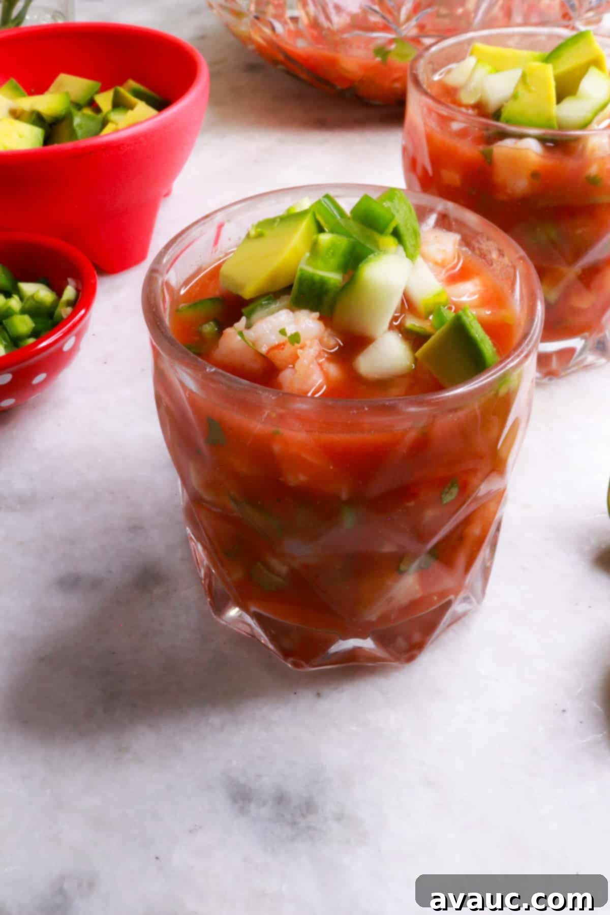 Vibrant Mexican Shrimp Cocktail 2 Glass full of Mexican shrimp cocktail, garnished with avocado and cilantro