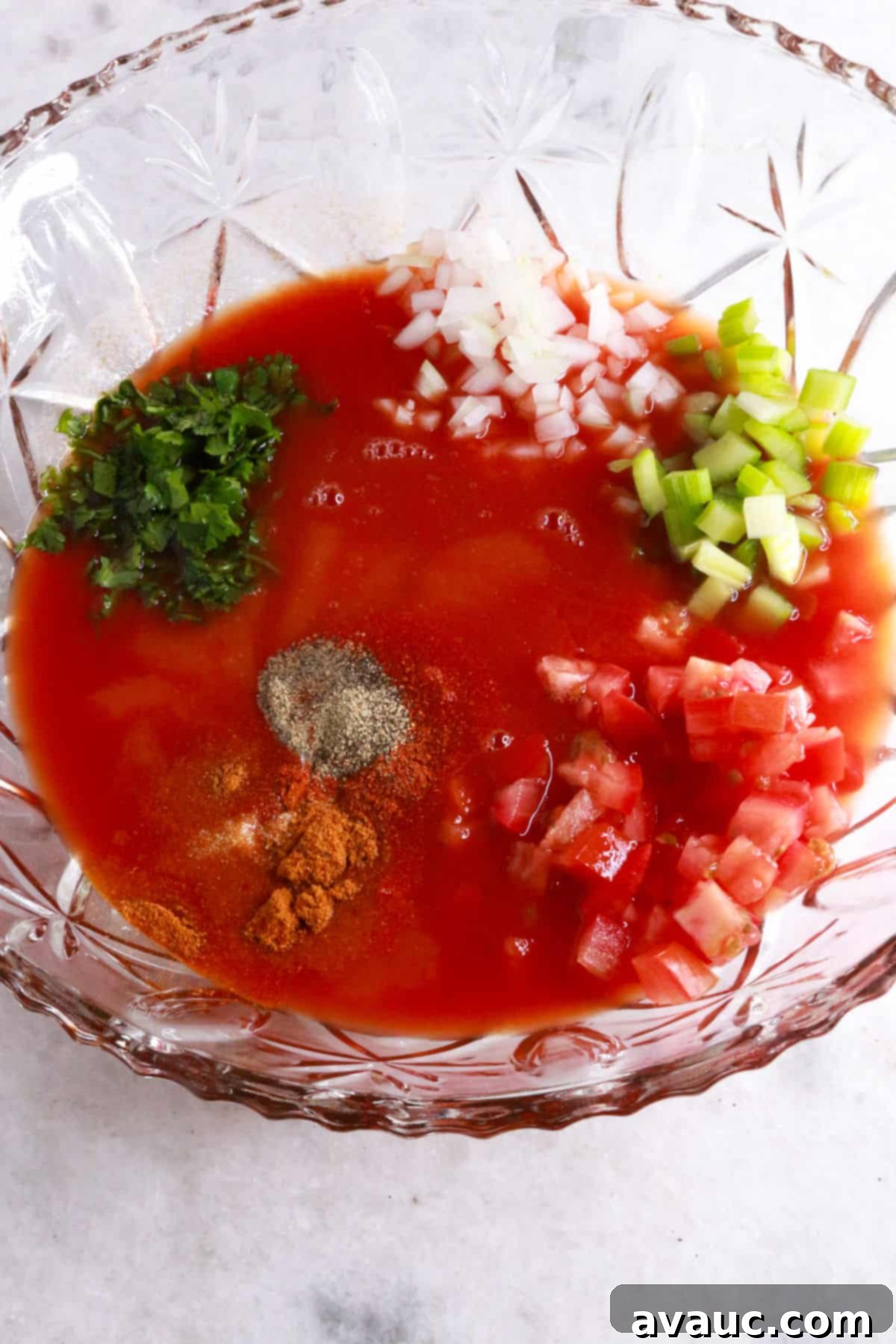 Vibrant Mexican Shrimp Cocktail 5 Glass mixing bowl containing tomato sauce, various spices, and freshly diced vegetables for Coctel de Camarones.