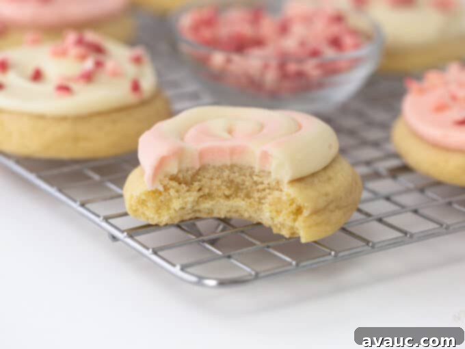 Festive Frosted Peppermint Sugar Cookies 3 Close-up of a fluffy frosted peppermint sugar cookie with a bite taken out, revealing its soft interior.