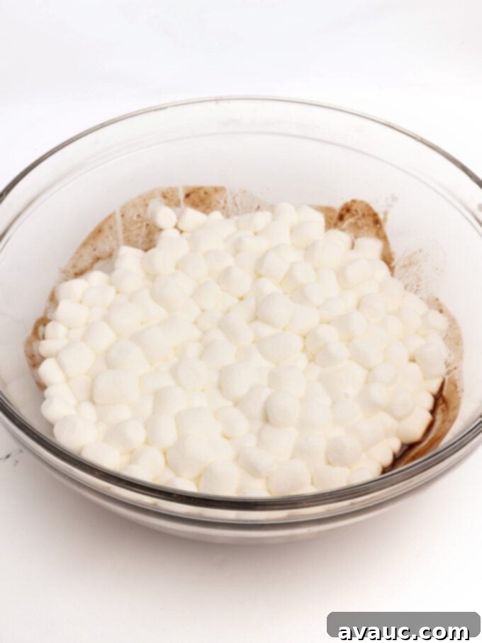 Spiced Gingerbread Krispie Treats 9 A bowl of melted chocolate with expanded, melted marshmallows, creating a gooey base