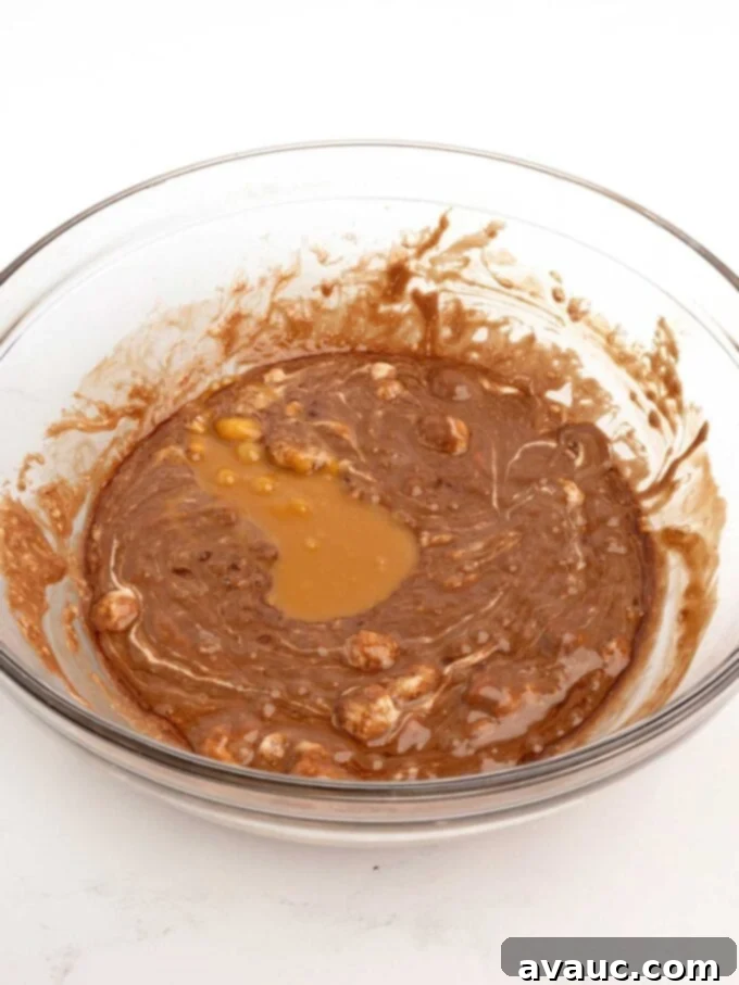 Spiced Gingerbread Krispie Treats 10 A bowl of melted chocolate with marshmallows, now combined with the melted caramel, showing a rich brown color