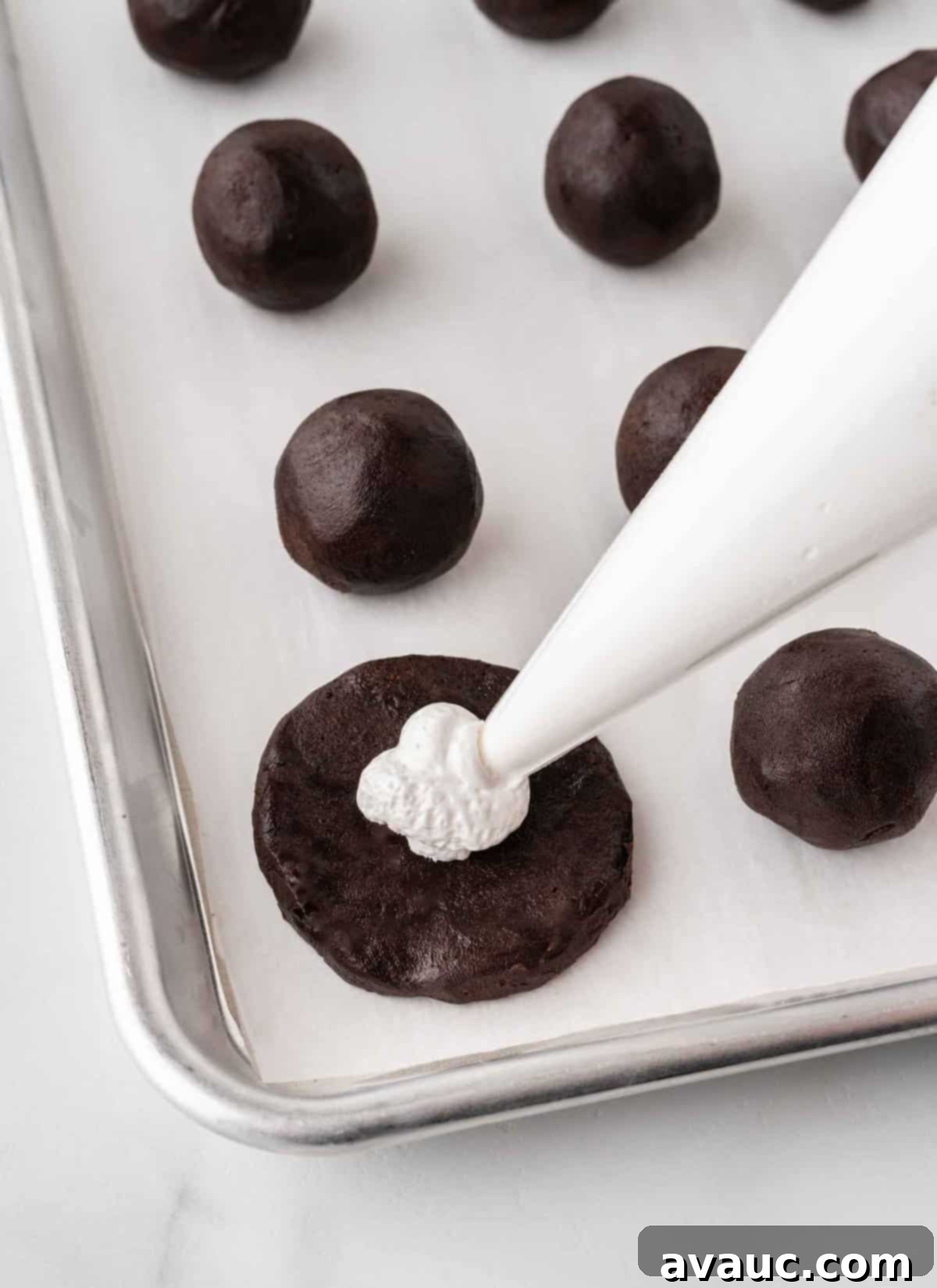 No-Dip Oreo Truffles 10 Marshmallow fluff being piped into the center of a flattened Oreo truffle dough.
