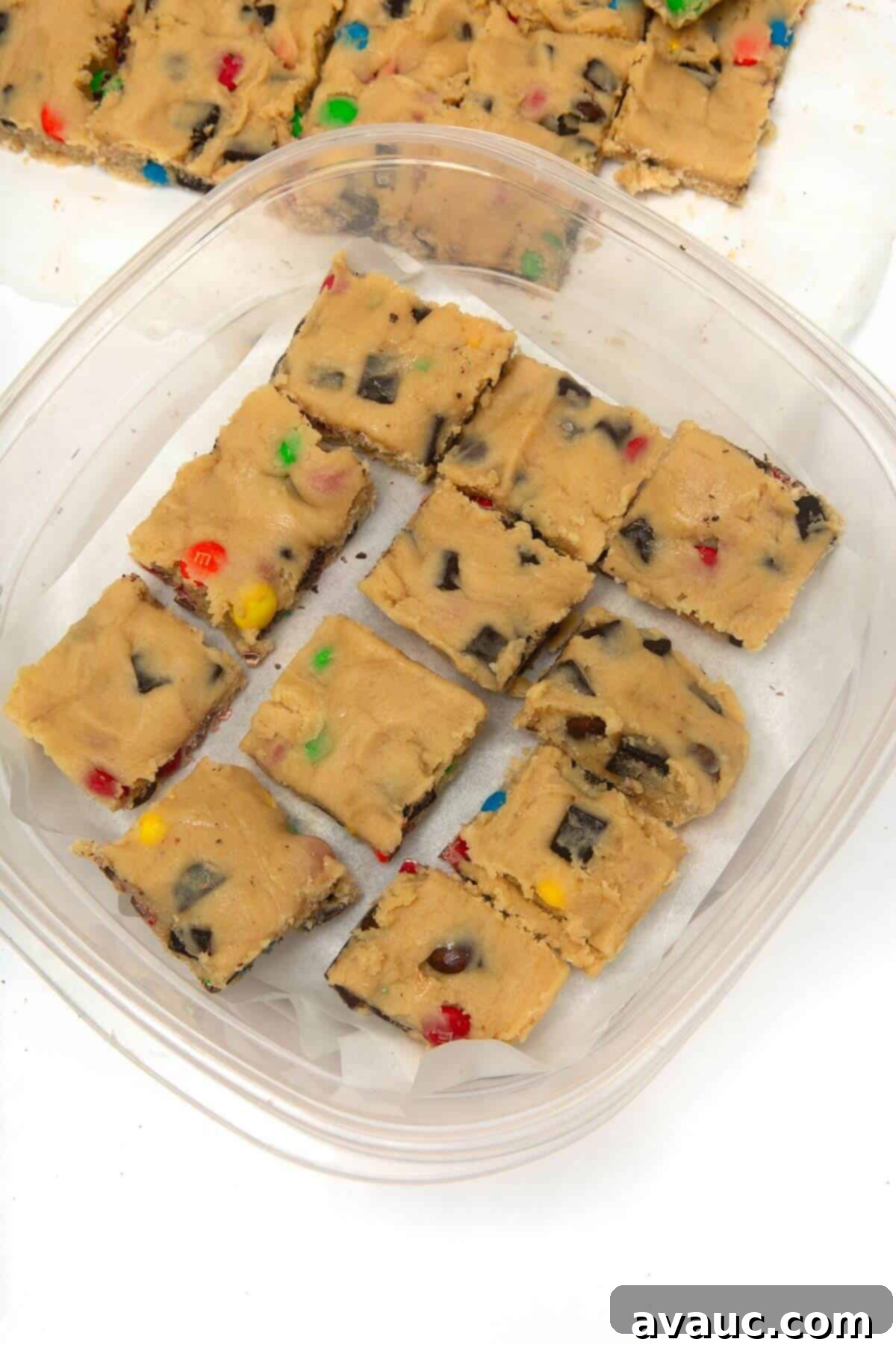 Frozen cookie dough squares neatly stacked in a clear plastic container, ready for long-term freezer storage.