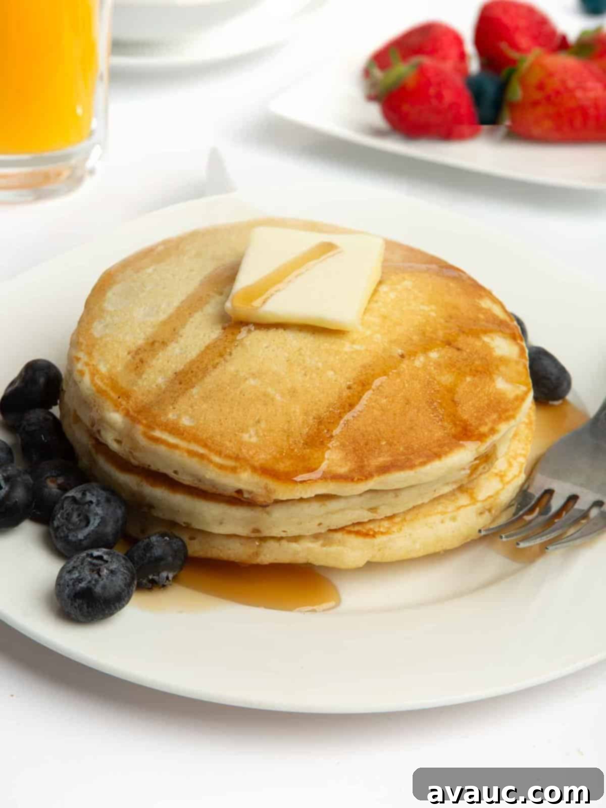 stack of fluffy homemade pancakes with butter and syrup