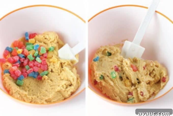 Adding sour patch kids candy to cookie dough and mixing with spatula to make sour patch kids cookies.
