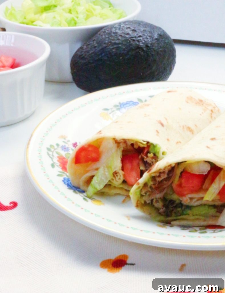 Close-up of a perfectly rolled Everyday Shredded Pork and Avocado Burrito, ready to be enjoyed. #porkburritos #mexicanfood #porkandavocadoburritos #easyrecipe