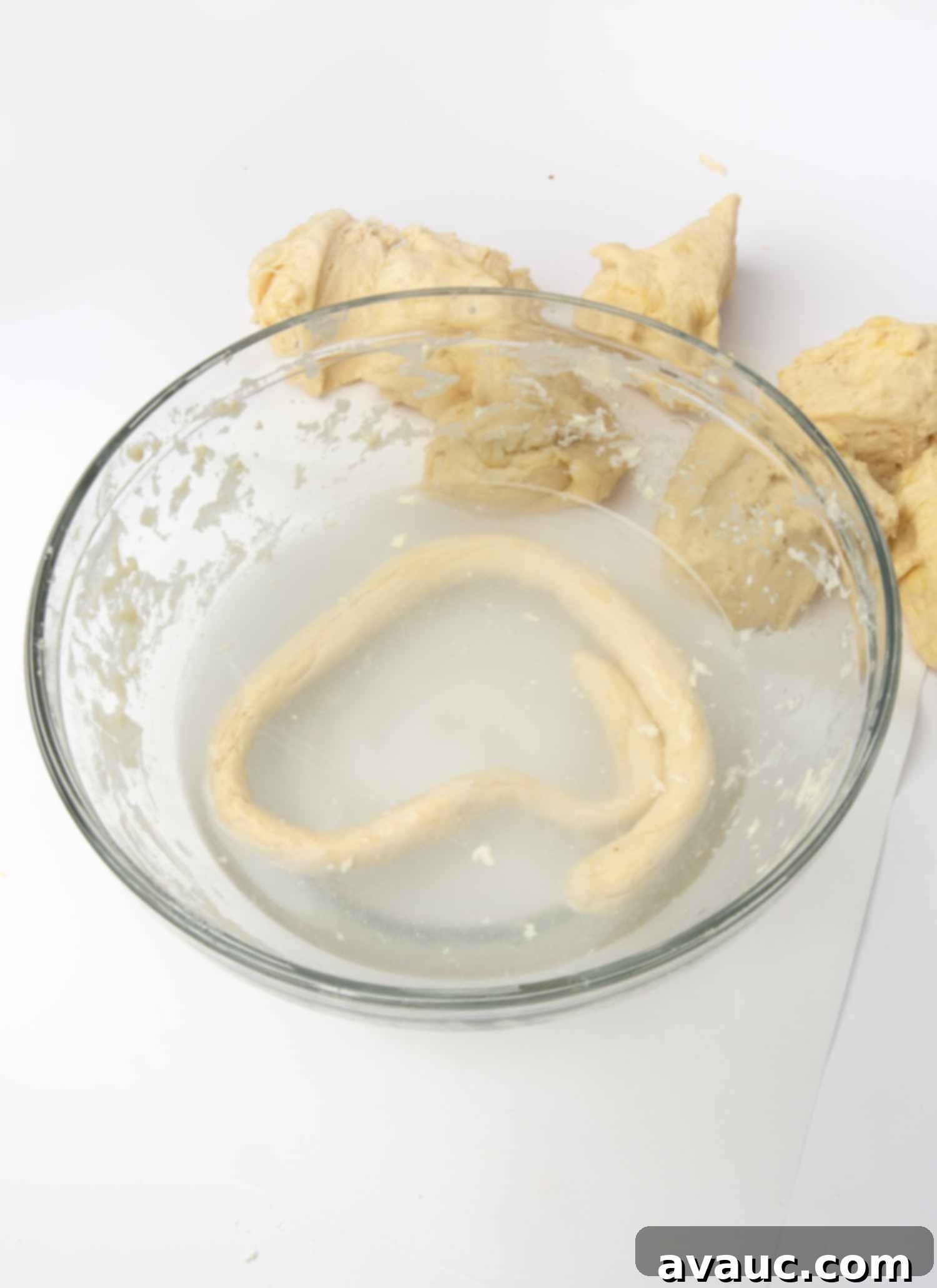1-Hour Pizza Pretzel Twists 11 Dough strip being dipped into a baking soda water bath.