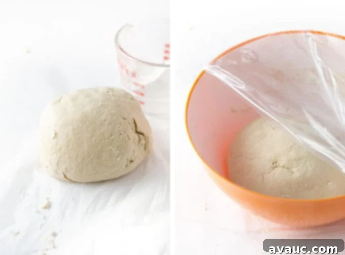 Effortless Soft Pretzel Rolls 7 Ball of dough in a bowl covered with plastic wrap, resting before rolling.