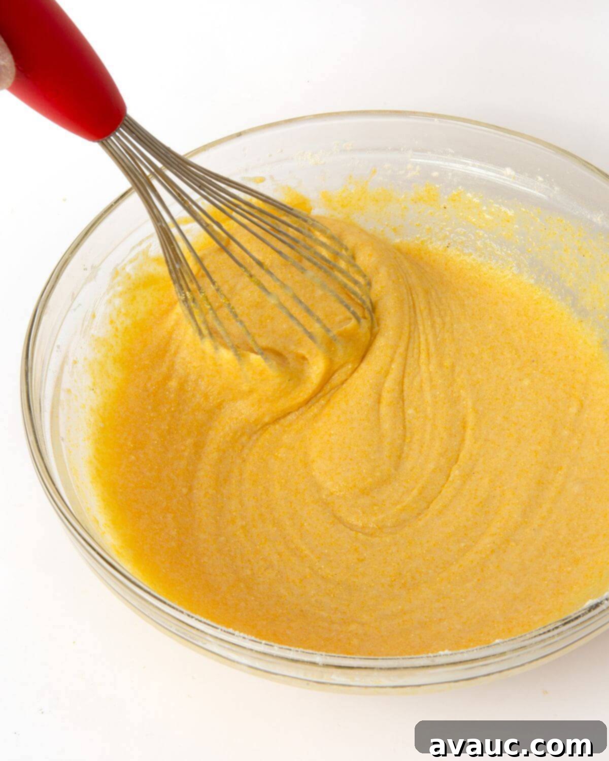 Corn Dog Muffin Poppers 6 Smooth corn muffin batter in a large mixing bowl with a whisk, ready for the hot dogs