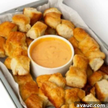 Pretzel Monkey Bread in a tray with cheese dipping sauce, ready to be served.