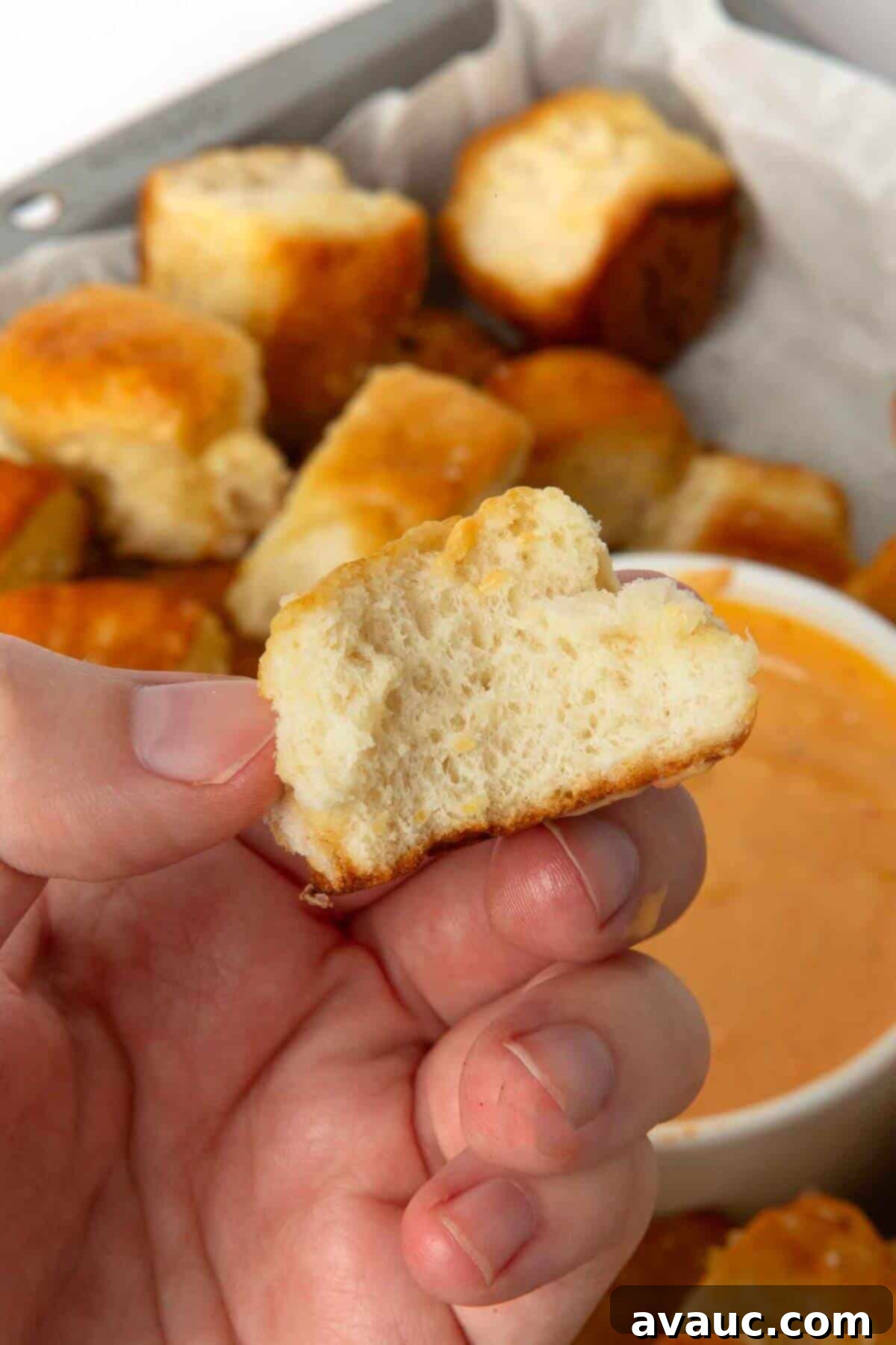 A hand holding a piece of pretzel monkey bread, showing its soft and fluffy interior.