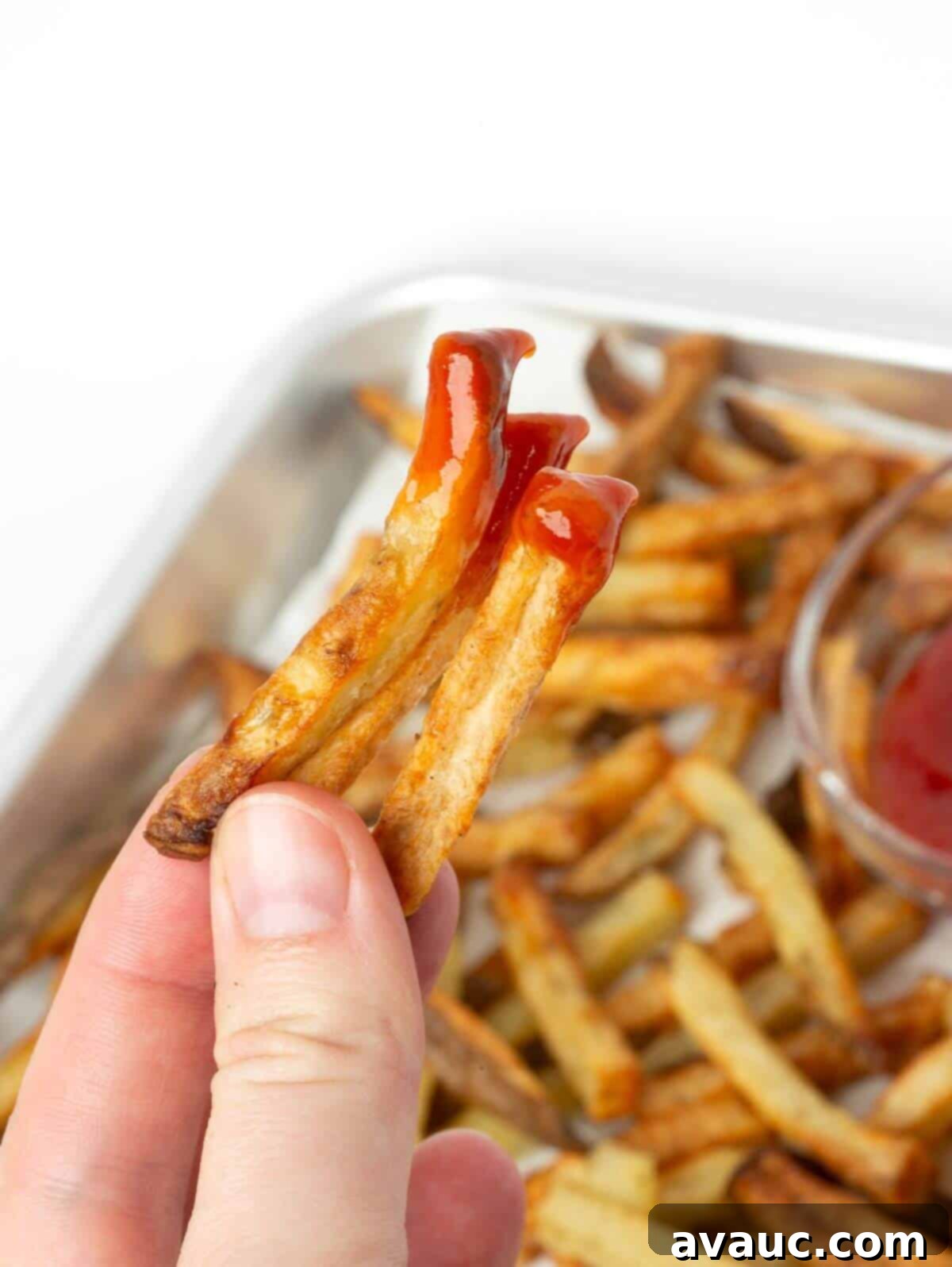 Close-up of a perfectly crispy air fryer french fry dipped in ketchup