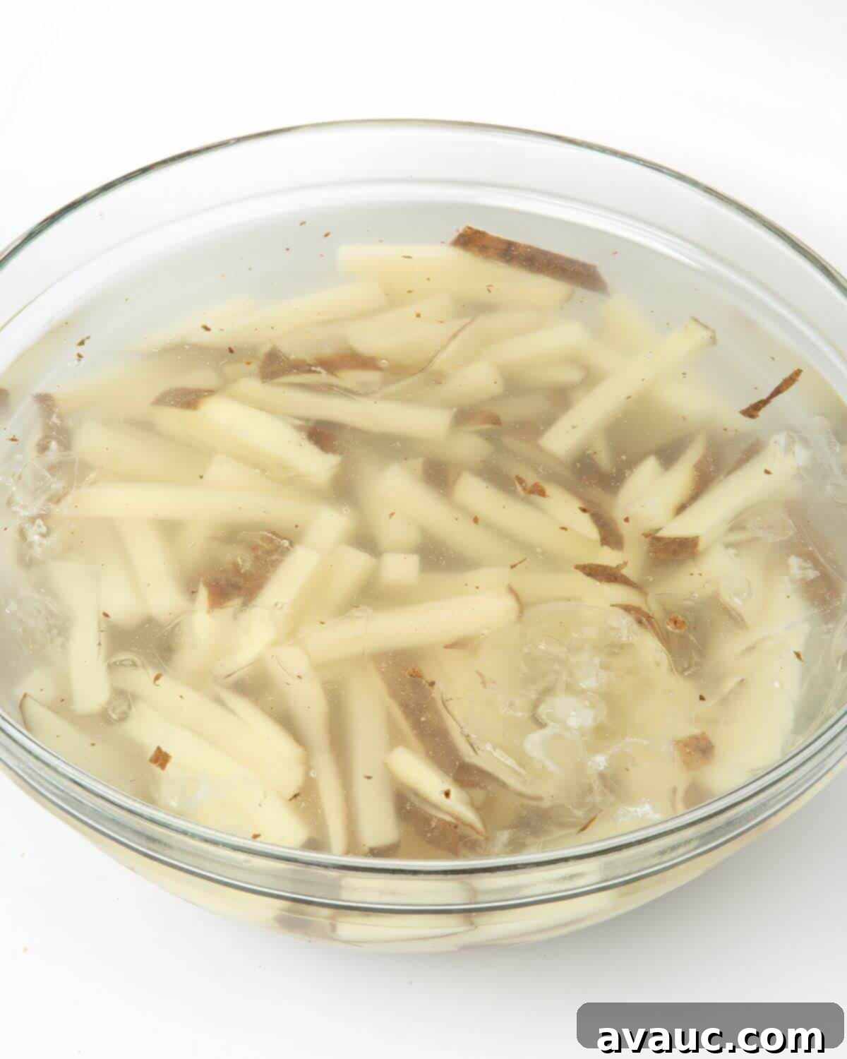 Cut potato fries soaking in a bowl of ice water to remove excess starch