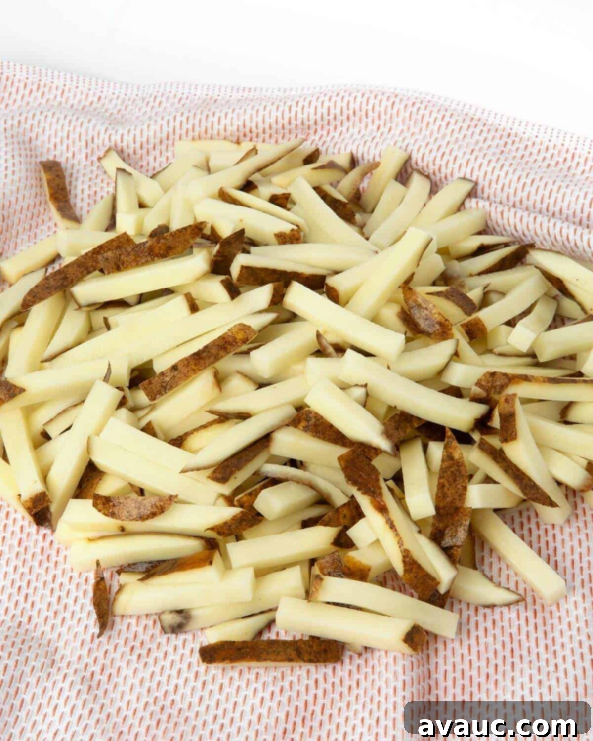 Thoroughly dried potato fries laid out on a kitchen towel before seasoning