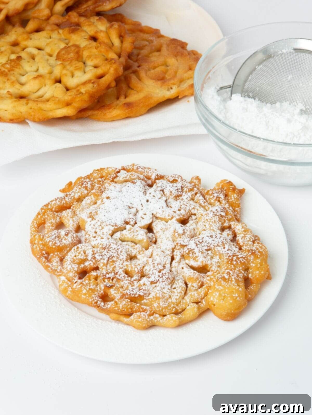 Simple Homemade Funnel Cakes 2 funnel cake on white plate with powdered sugar