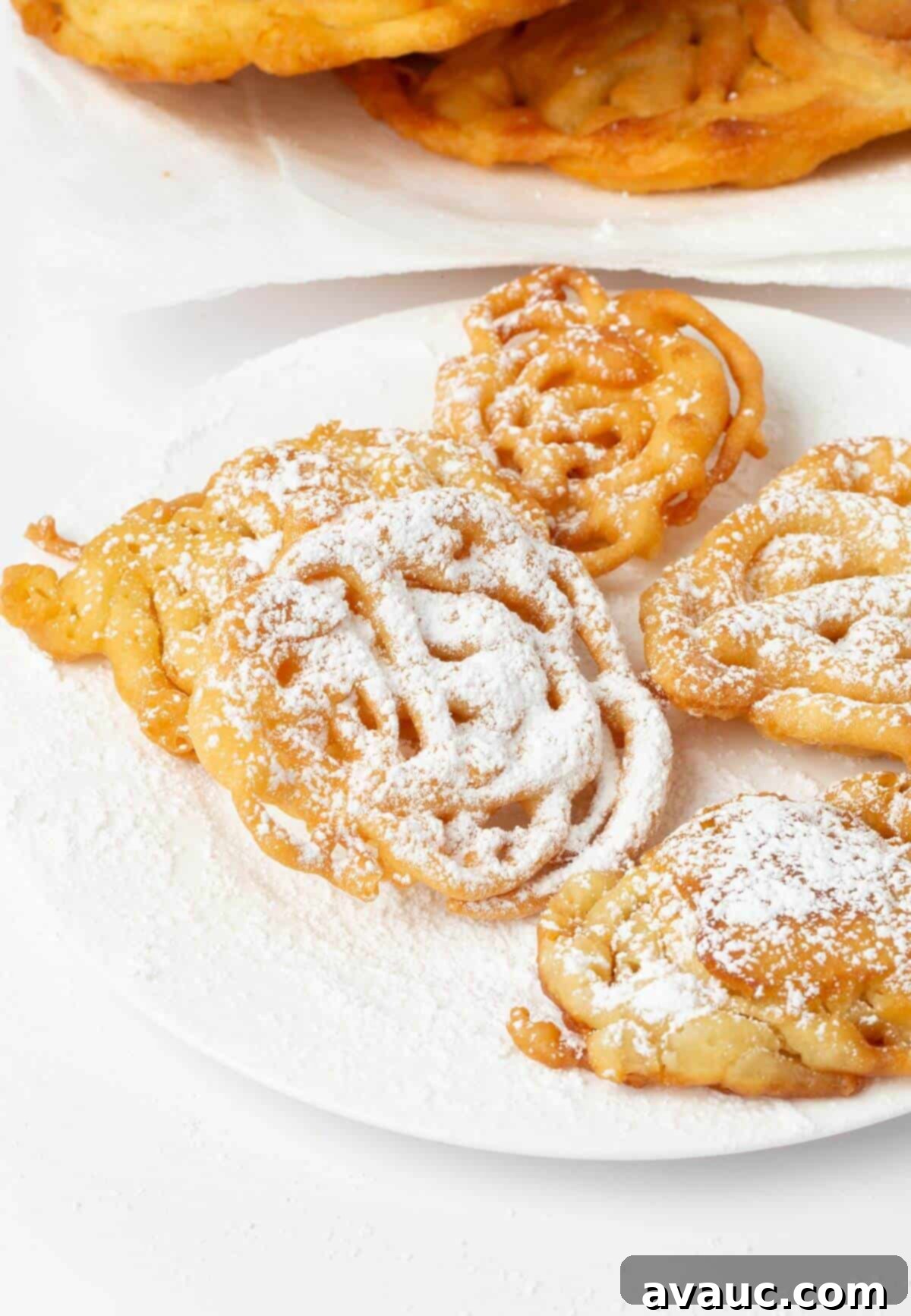 Simple Homemade Funnel Cakes 11 easy funnel cakes on white plate with powdered sugar
