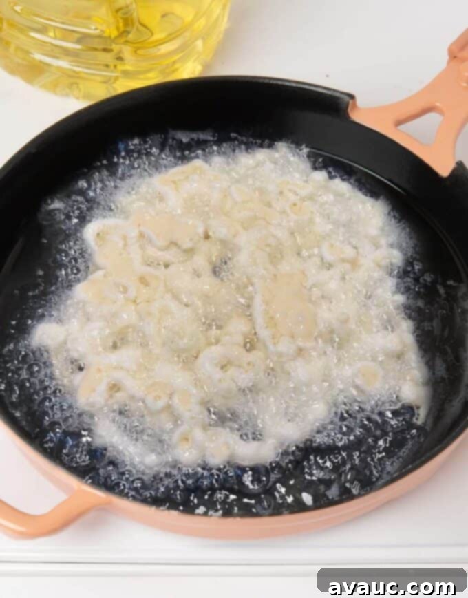 Simple Homemade Funnel Cakes 7 funnel cake batter being fried in hot oil in pink skillet