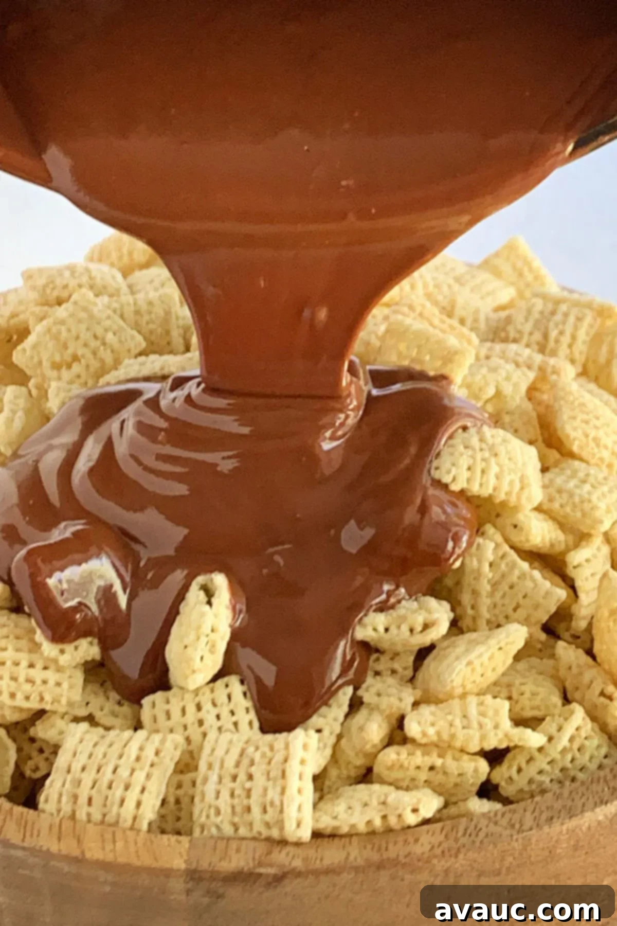 A luscious mixture of melted peanut butter, dairy-free butter, and chocolate being poured over a bowl of crispy Rice Chex cereal.