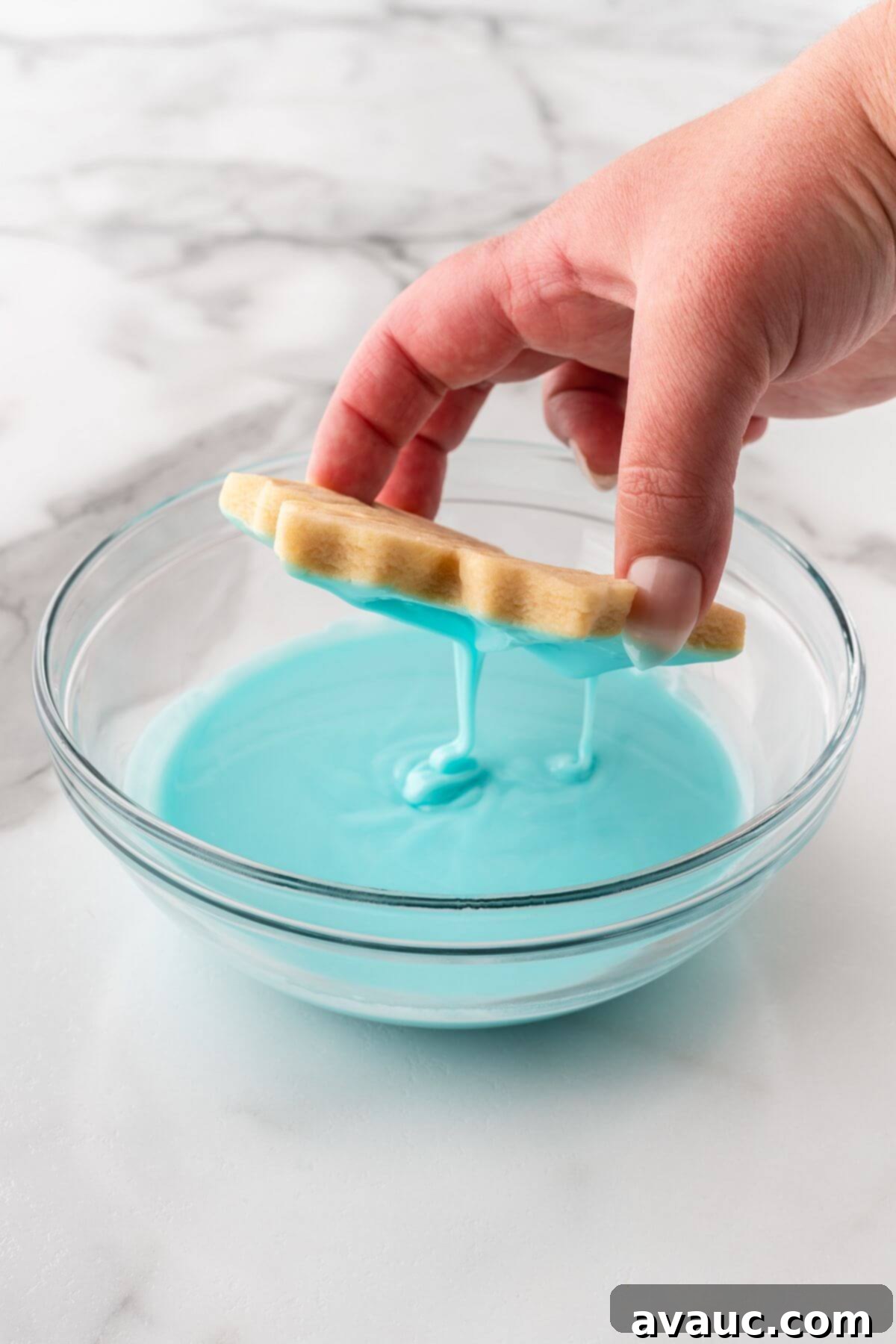 Dipping a snowflake sugar cookie into blue glaze icing