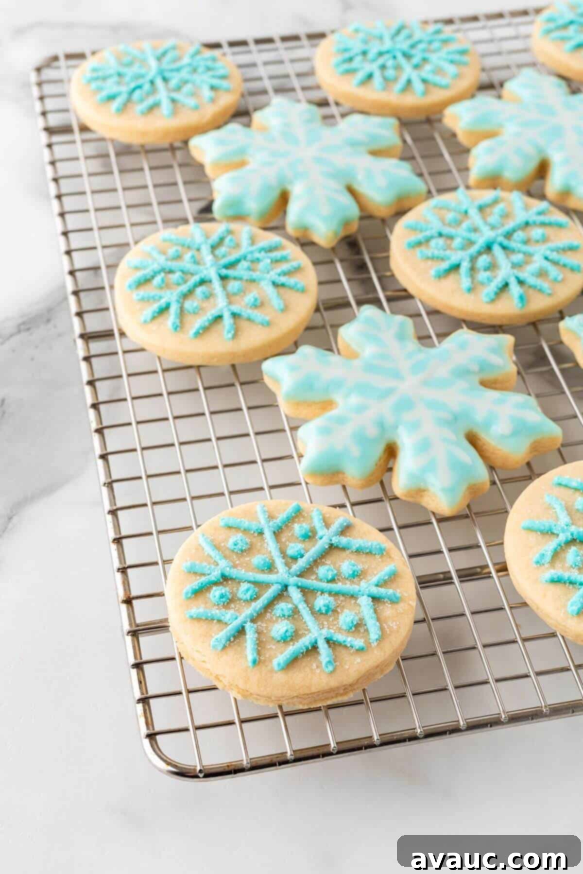 Snowflake sugar cookies cooling on a wire rack after being baked and frosted