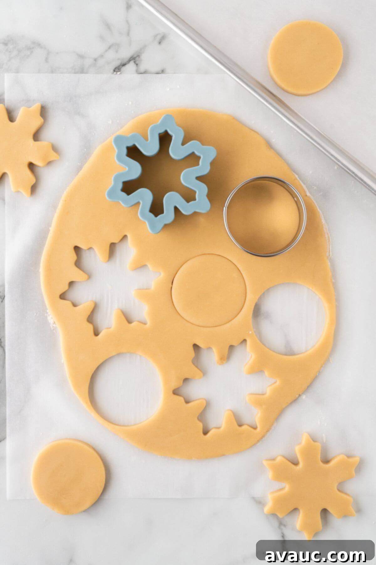 Cutting out snowflake and circle sugar cookie dough shapes