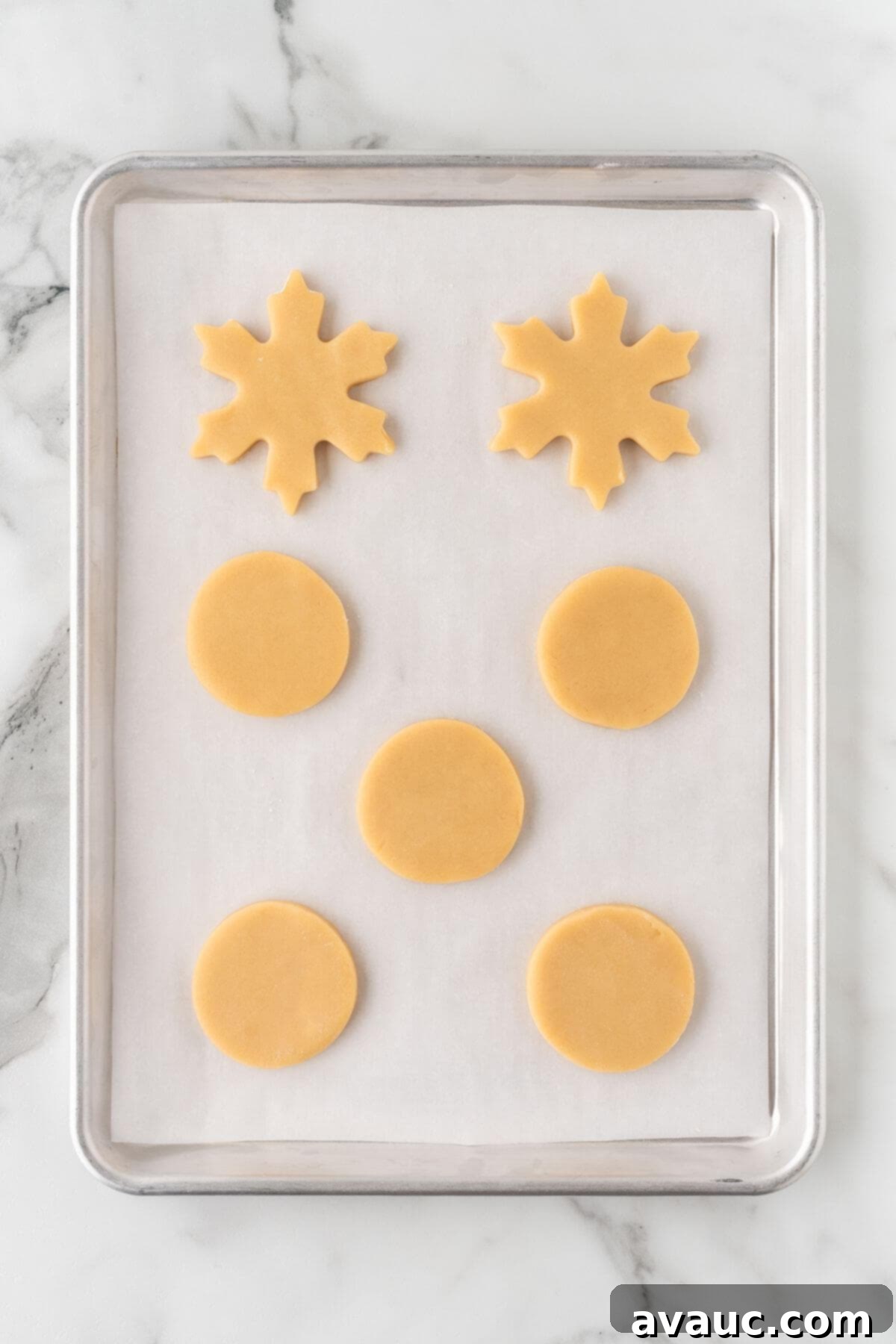 Cut out sugar cookies arranged on a parchment-lined baking sheet