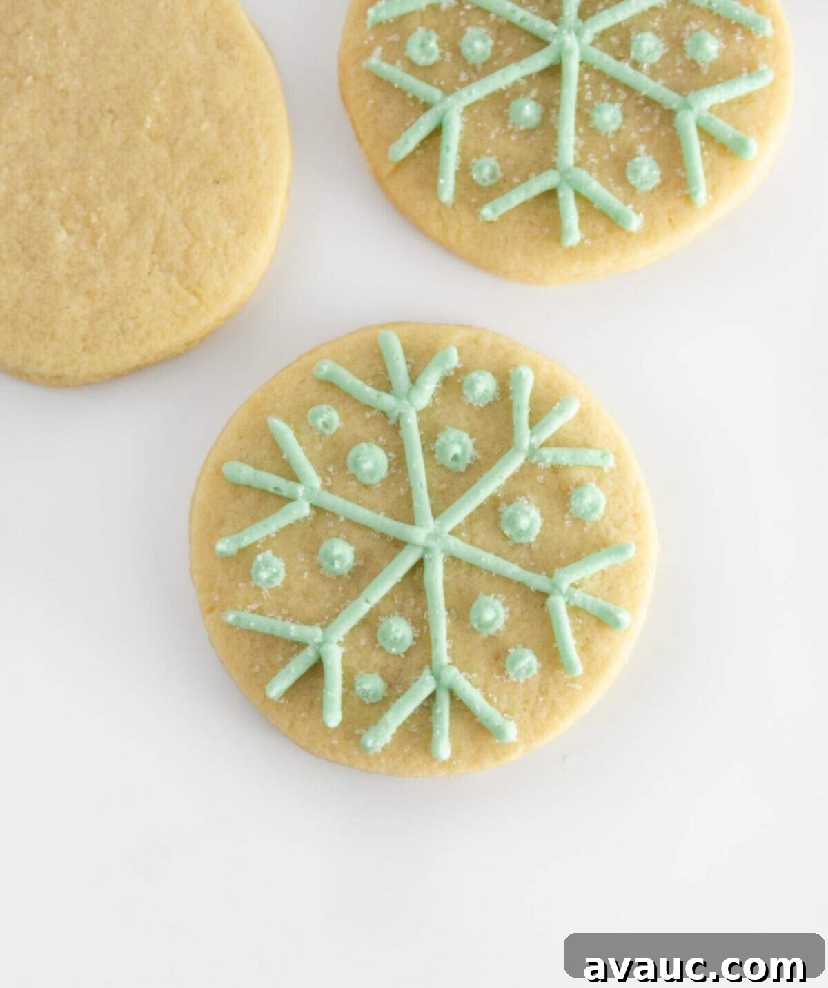 Round sugar cookie with piped blue snowflake design and white sparkling sugar