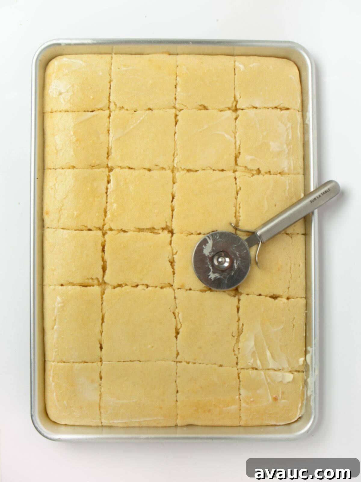 Sheet Pan Pancake Perfection 3 Sliced sheet pan pancakes on a rimmed baking sheet, cut with a pizza cutter, showing their fluffy texture.