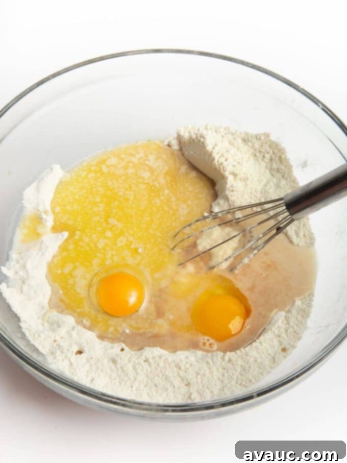 Sheet Pan Pancake Perfection 5 Wet ingredients being mixed into dry ingredients in a large mixing bowl with a whisk for pancake batter.