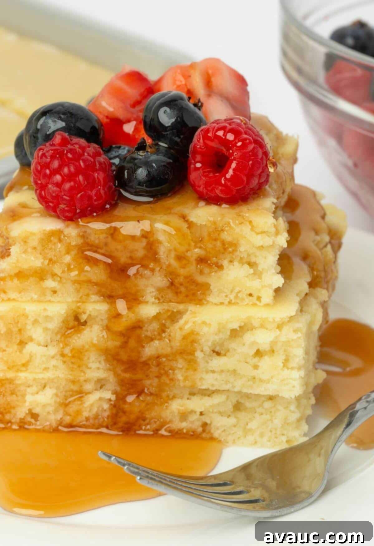 Sheet Pan Pancake Perfection 9 A plate of sheet pan pancakes topped with syrup and fresh berries, next to a fork, ready to be enjoyed.