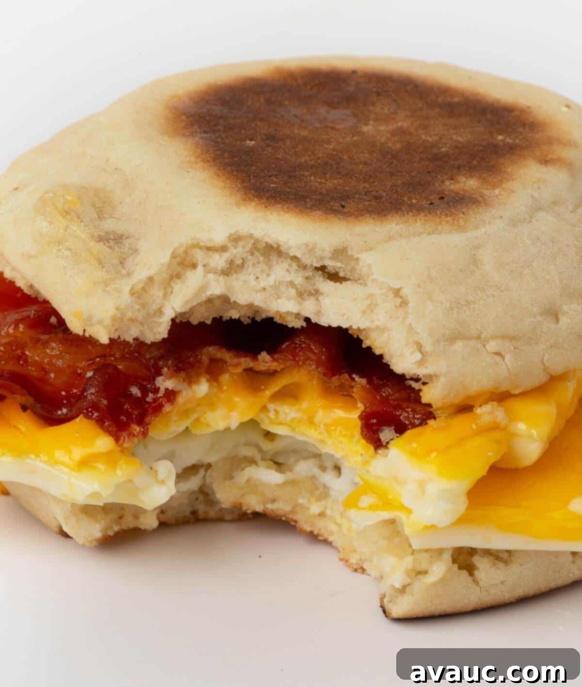 On-the-Go Breakfast Sandwiches 3 Freezer breakfast sandwich with a bite taken out, showing the egg, cheese, and bacon layers