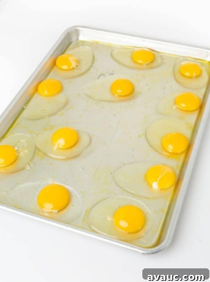 On-the-Go Breakfast Sandwiches 5 Eggs cracked directly on a greased baking sheet, preparing for freezer breakfast sandwiches