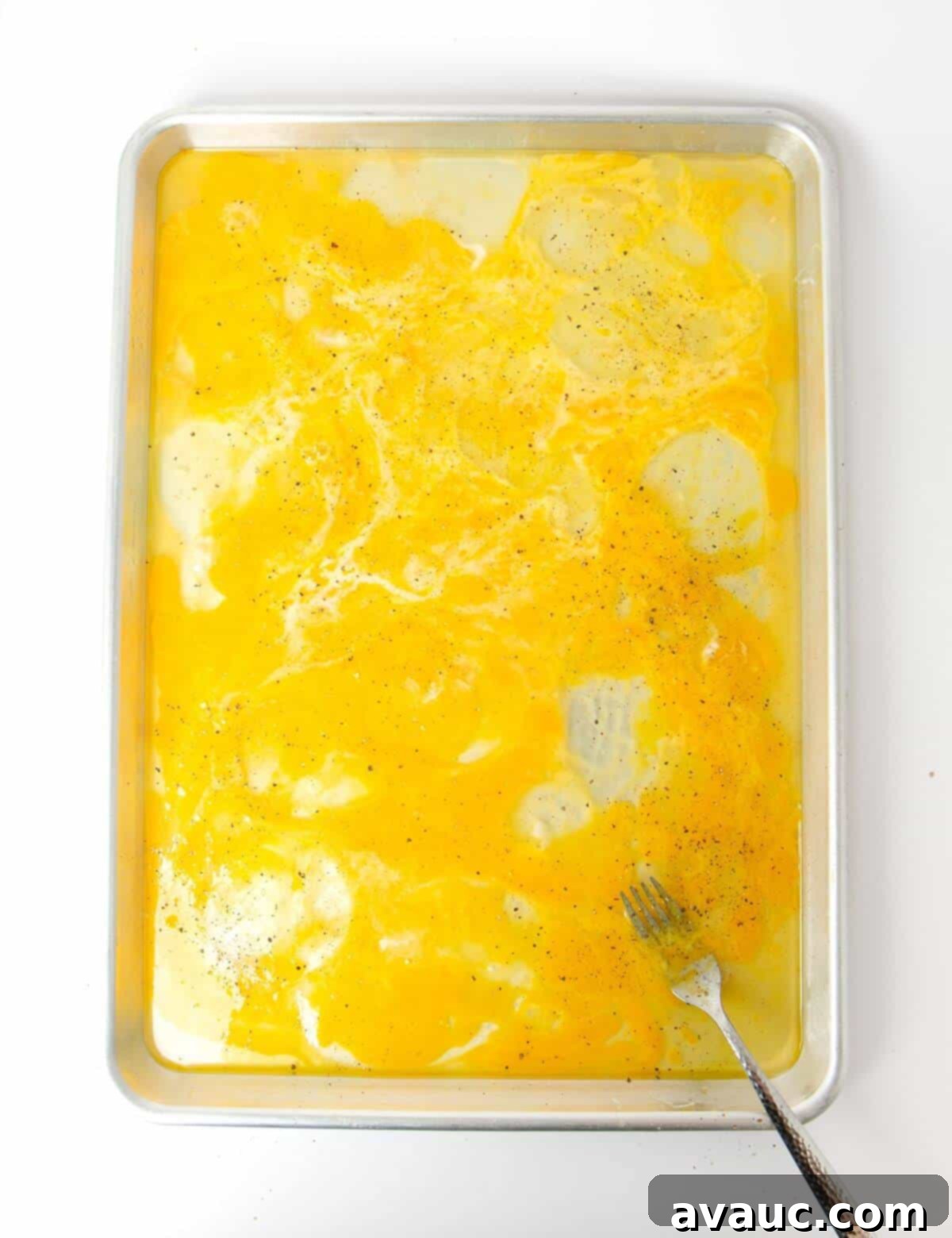 egg yolks and egg whites mixed together with fork on baking sheet