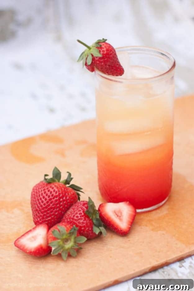 Refreshing Summer Spritzer with Orange Juice, Lemon-Lime Soda, and Grenadine, garnished with fresh strawberries. Design Eat Repeat