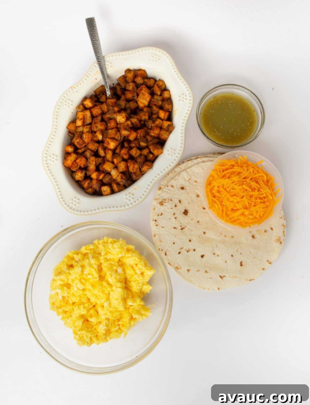 all ingredients for breakfast burritos laid out on a wooden cutting board