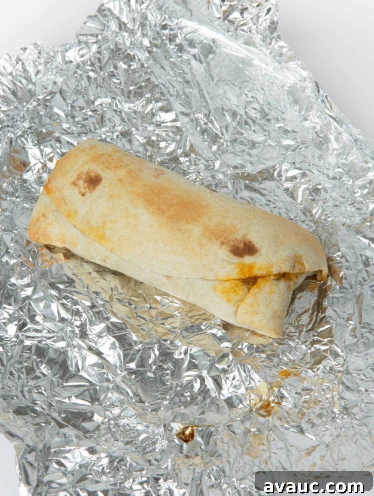 baked breakfast burrito on a piece of tin foil