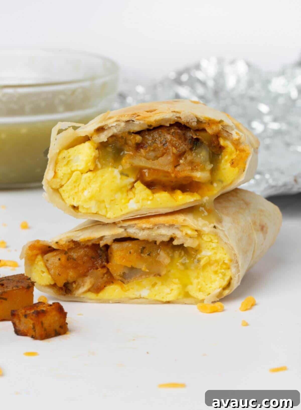 breakfast burrito cut in half on a wooden cutting board, garnished with cilantro
