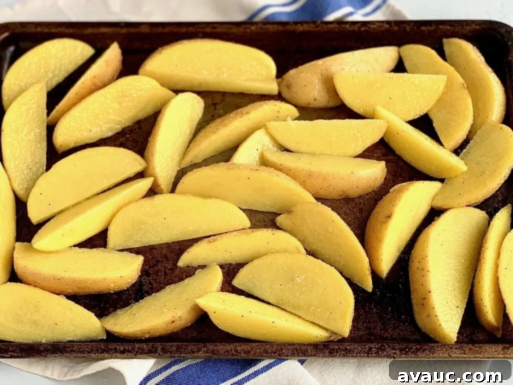 Golden Crispy Potato Wedges 6 Seasoned potato wedges on a baking sheet ready for the oven