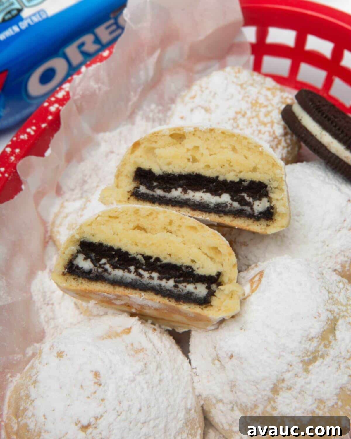 Ultimate Air Fried Oreos 12 A perfectly air fried Oreo, cut in half, sitting in a red basket with a sprinkle of powdered sugar, showing the soft interior.