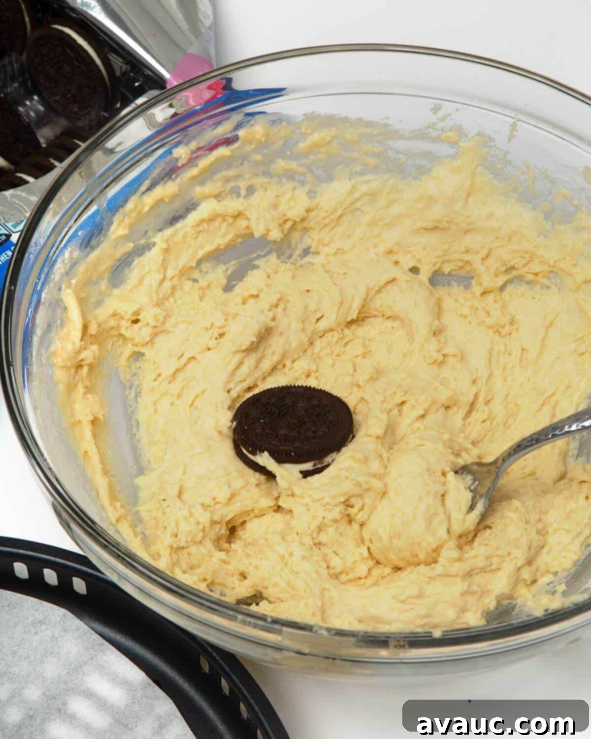 Ultimate Air Fried Oreos 7 Oreo cookie being dipped into pancake batter with a fork in a glass mixing bowl.