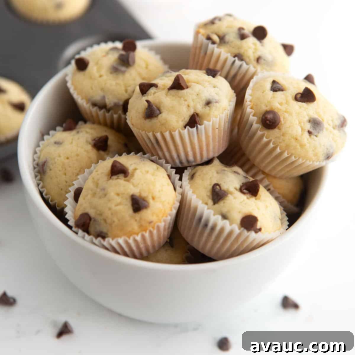 Bowl overflowing with soft and moist mini chocolate chip muffins, perfect for a quick breakfast or snack.