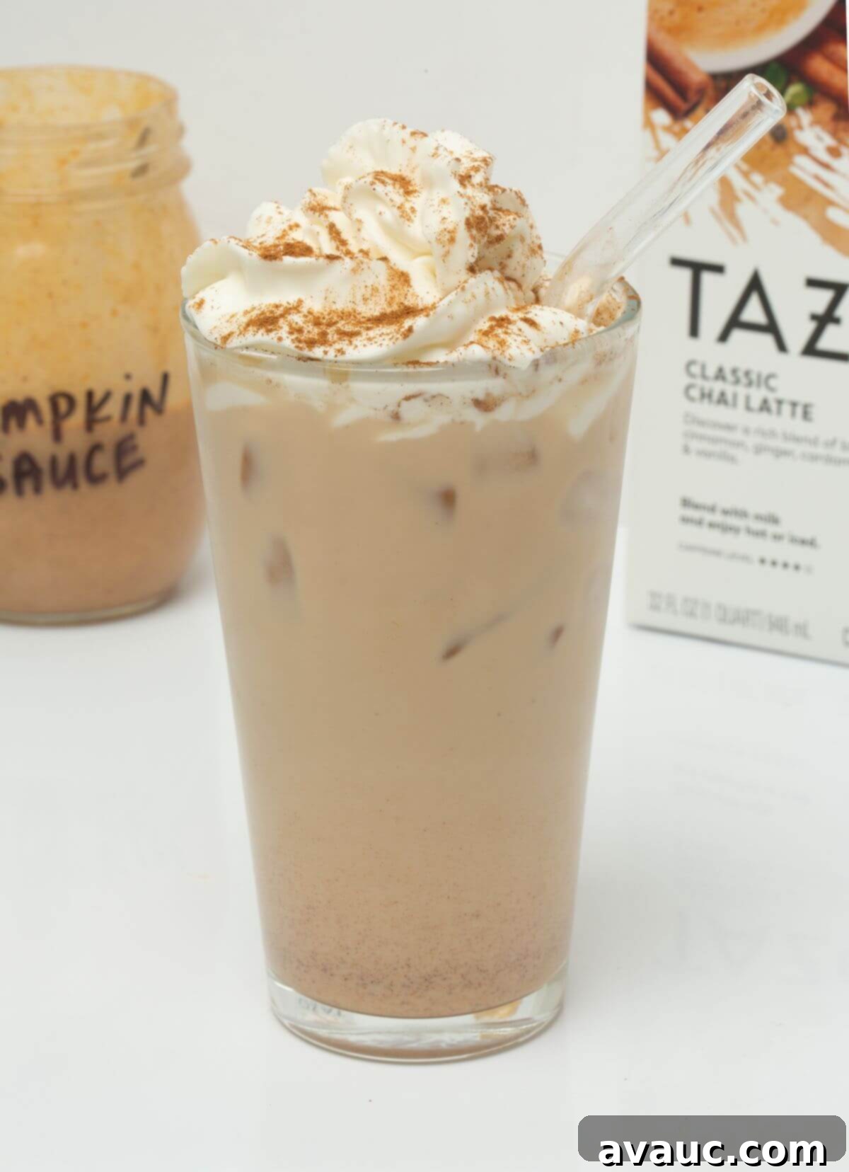 Autumn Pumpkin Chill Latte 2 Iced pumpkin cream chai with glass straw in a tall glass, garnished with a sprinkle of cinnamon.