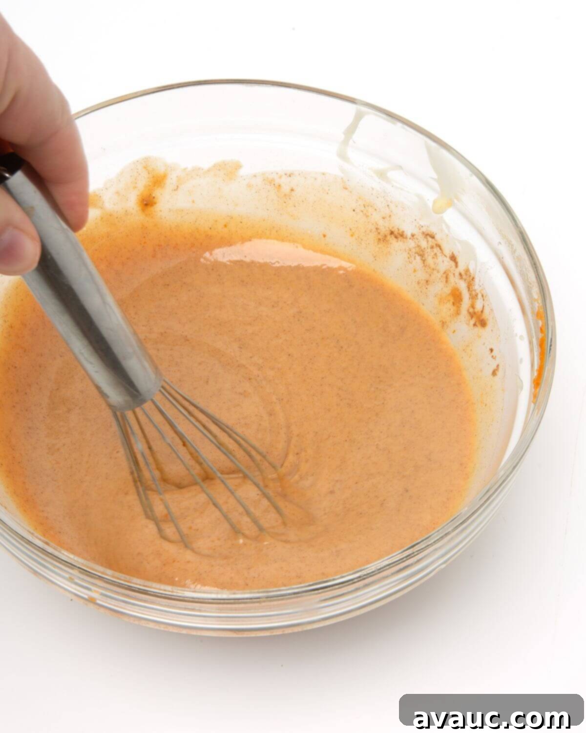 Handcrafted Pumpkin Spice Syrup 2 All ingredients for homemade pumpkin spice sauce mixed in a glass bowl with a whisk, showing the creamy texture.