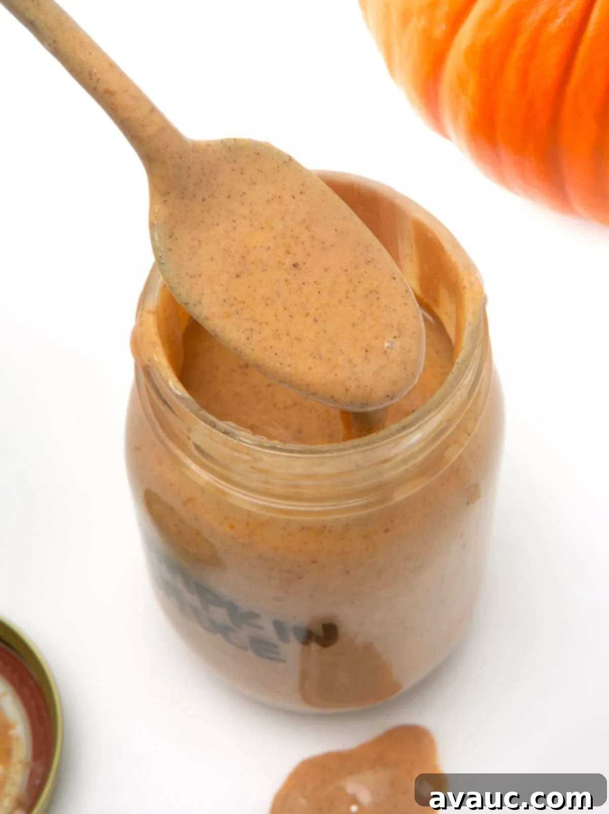 Handcrafted Pumpkin Spice Syrup 3 A spoon dipping into a jar of rich, homemade pumpkin spice sauce, ready for use.